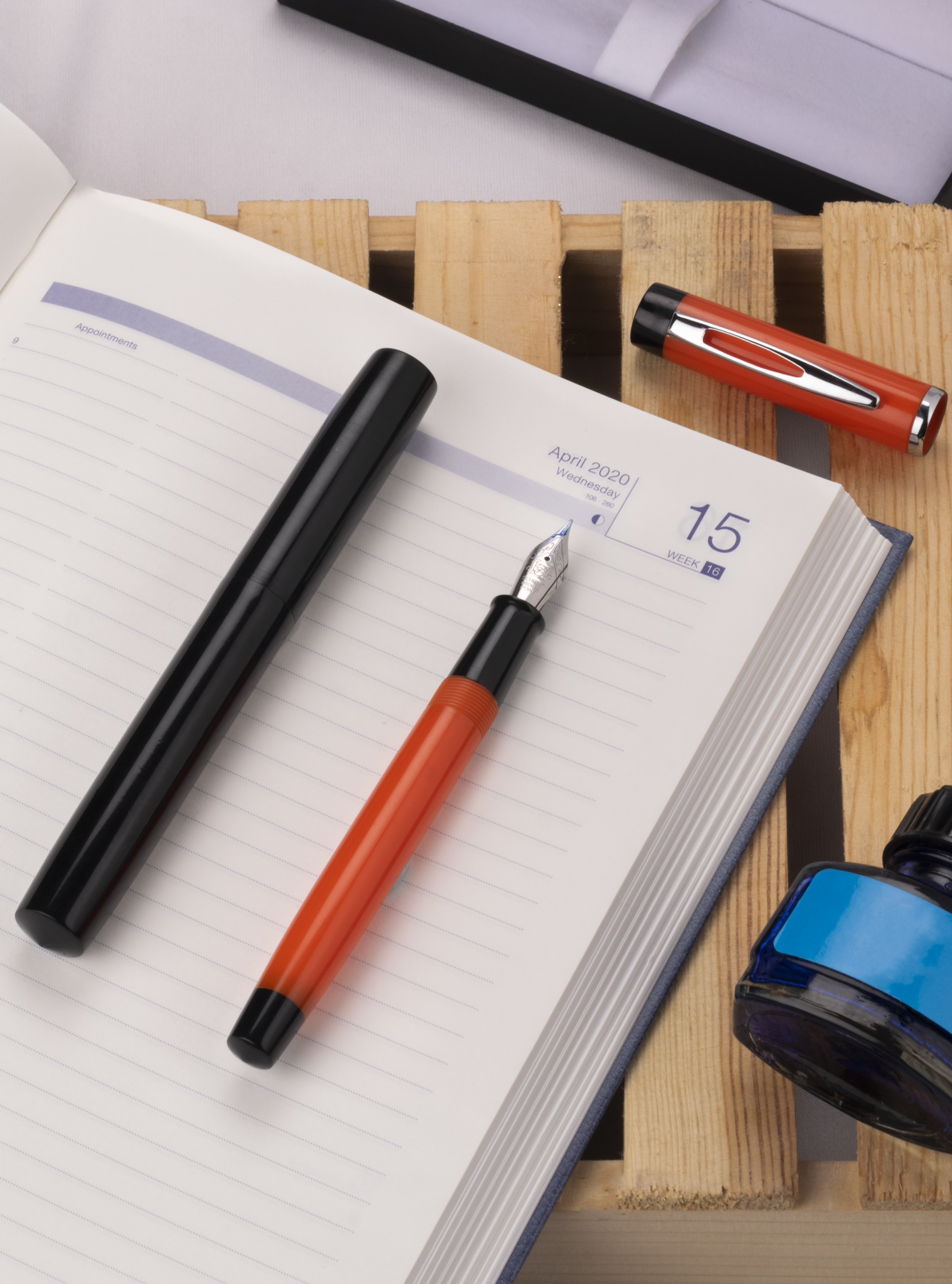 Red and black fountain pen on open diary — product photography